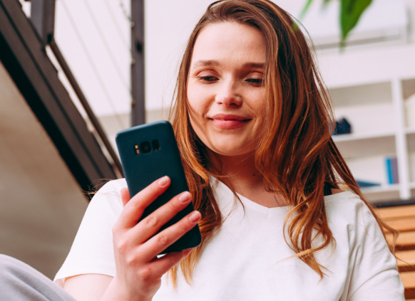 Young woman smiling and looking at her phone