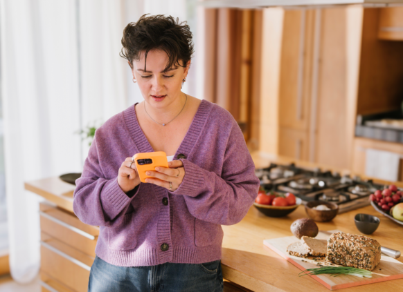 Young woman in a kitchen looking at her phone