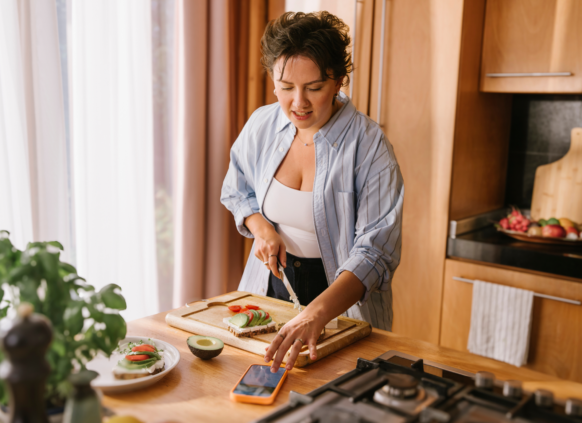 Woman cooking meal with a recipe on the Oviva app