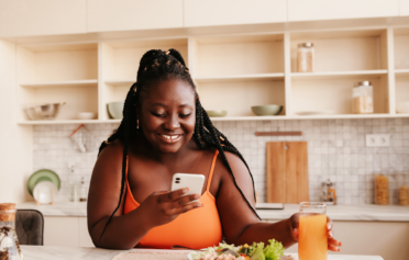 Woman smiling at her phone about to eat a meal