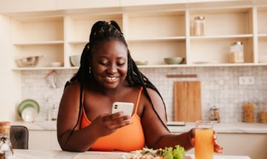 Woman smiling at her phone about to eat a meal