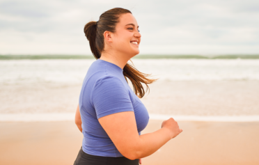 Overweight woman running on the beach