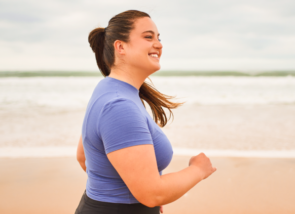 Overweight woman running on the beach