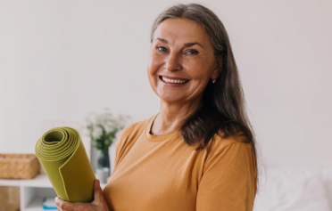 Older woman smiling with her exercise mat