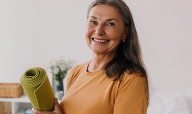 Older woman smiling with her exercise mat