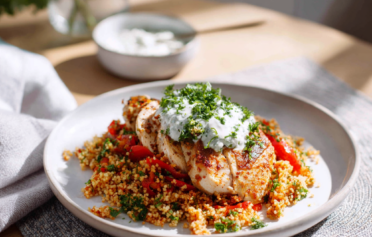 Healthy recipe of turkey with bulgur wheat, peppers & herb yoghurt on a white plate