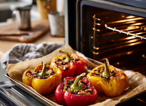 Baking tray coming out of the oven oven four stuffed, roasted peppers