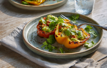 Stuffed peppers served on two ceramic plates on a light wooden table